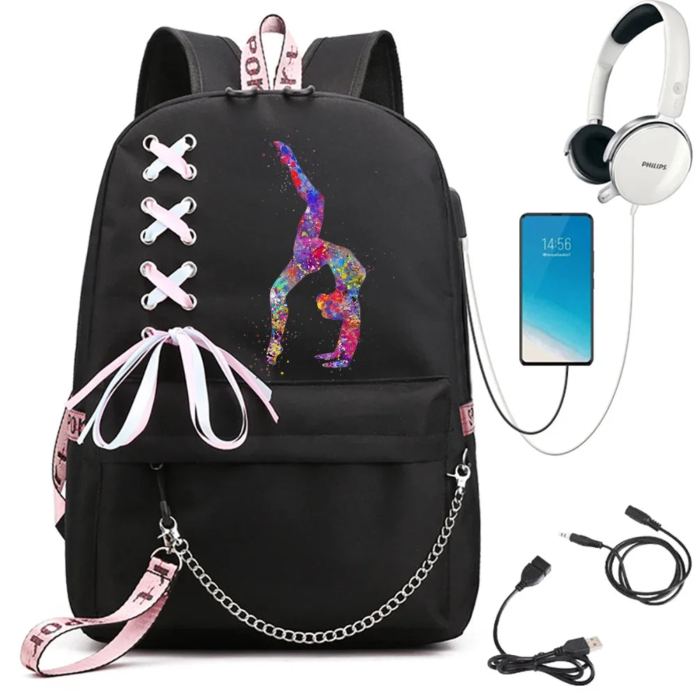 A black backpack with a single-leg handstand gymnast print, light pink ribbon bow and pink webbing, beside electronics props.