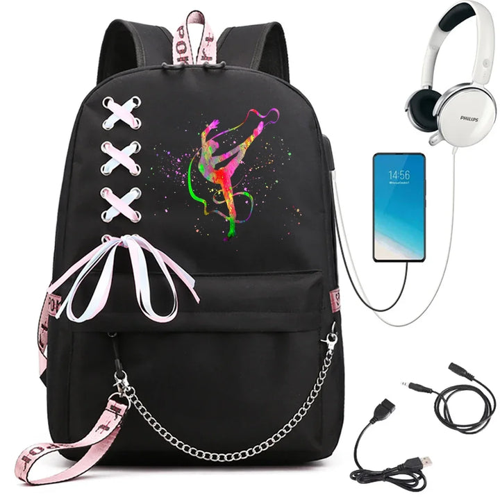 A black school backpack with rainbow ribbon gymnast artwork, ribbon crosses, pink trim and chain, beside demonstration props.
