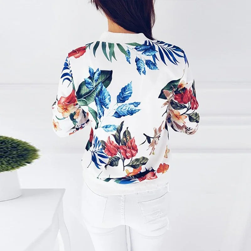 White floral zip jacket viewed from the back on a model, showing large red flowers, blue leaves, and the matching ribbed hem.
