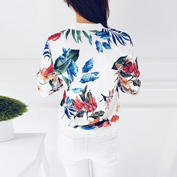 White floral zip jacket viewed from the back on a model, showing large red flowers, blue leaves, and the matching ribbed hem.