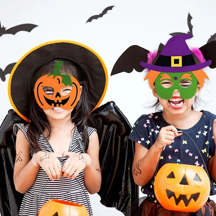 Two children wearing pumpkin and green witch costume masks, with a black hat and decorative bats for a Halloween party scene.