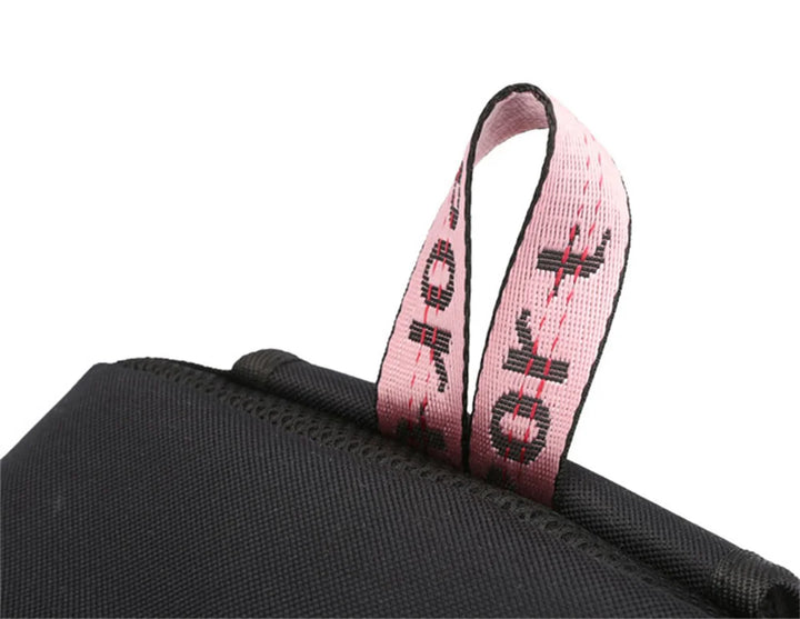 Close-up of the pink woven top handle featuring SPORT lettering where it joins black fabric of the school backpack in detail.