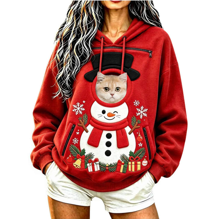 Model wearing a red snowman hoodie with a cat at the circular front opening, with a hood, long sleeves and black zip pockets.