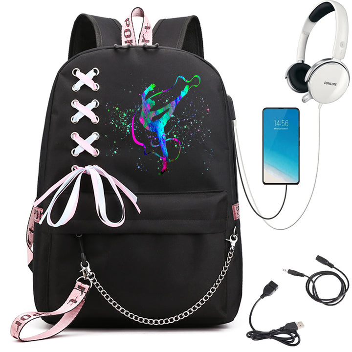 A black school backpack featuring blue and green gymnast artwork, pale ribbon bow and silver chain, beside electronics props.