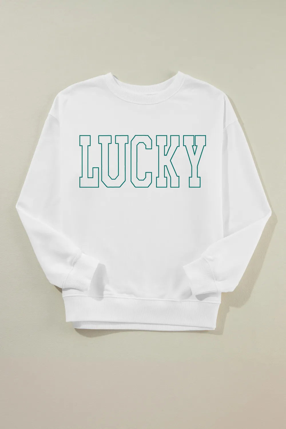 “Smiling woman in LUCKY graphic sweatshirt sitting on a bench with autumn leaves around”

