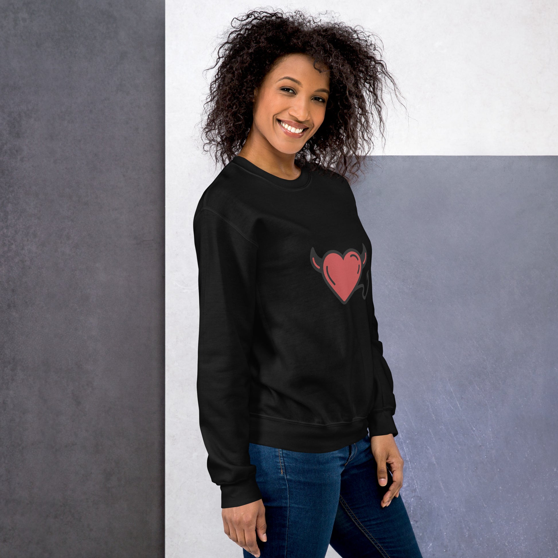 Woman in light gray unisex sweatshirt with red horned heart print

