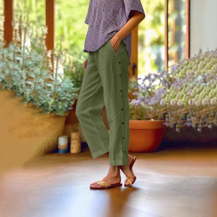Person wearing green pants and a patterned top in a room with plants