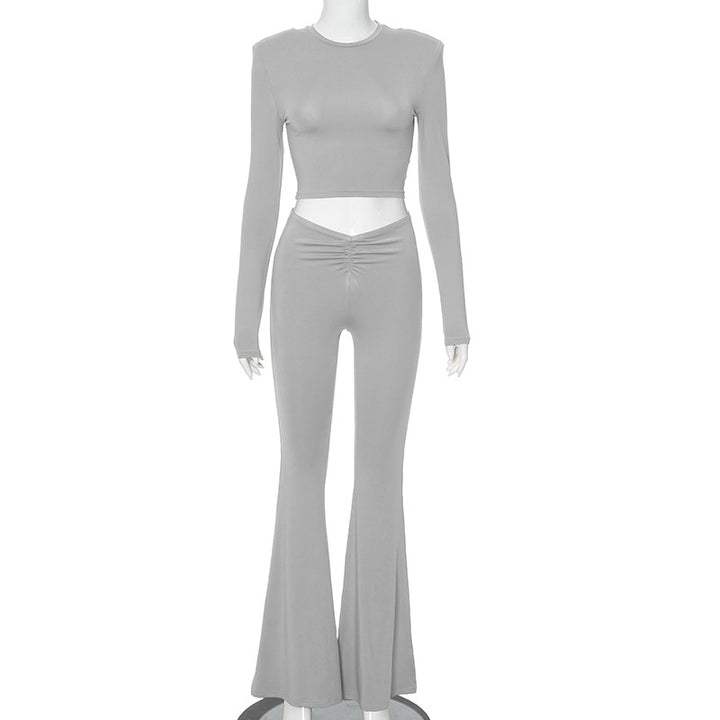 full body gray pleated crop top and pants set on European model with subtle exposed midriff in studio lighting