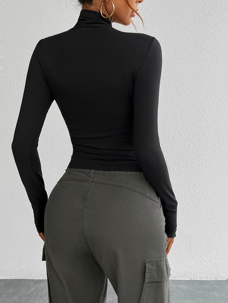 Person wearing a black long-sleeve top and gray cargo pants against a white wall.