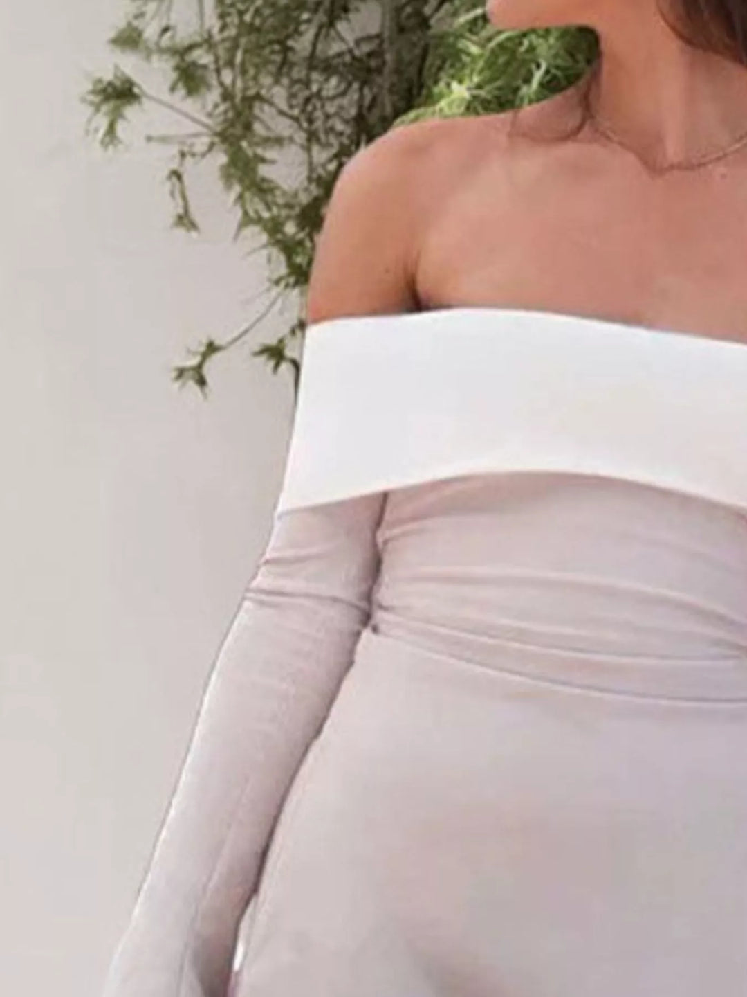 Person wearing a white off-shoulder top with a blurred background