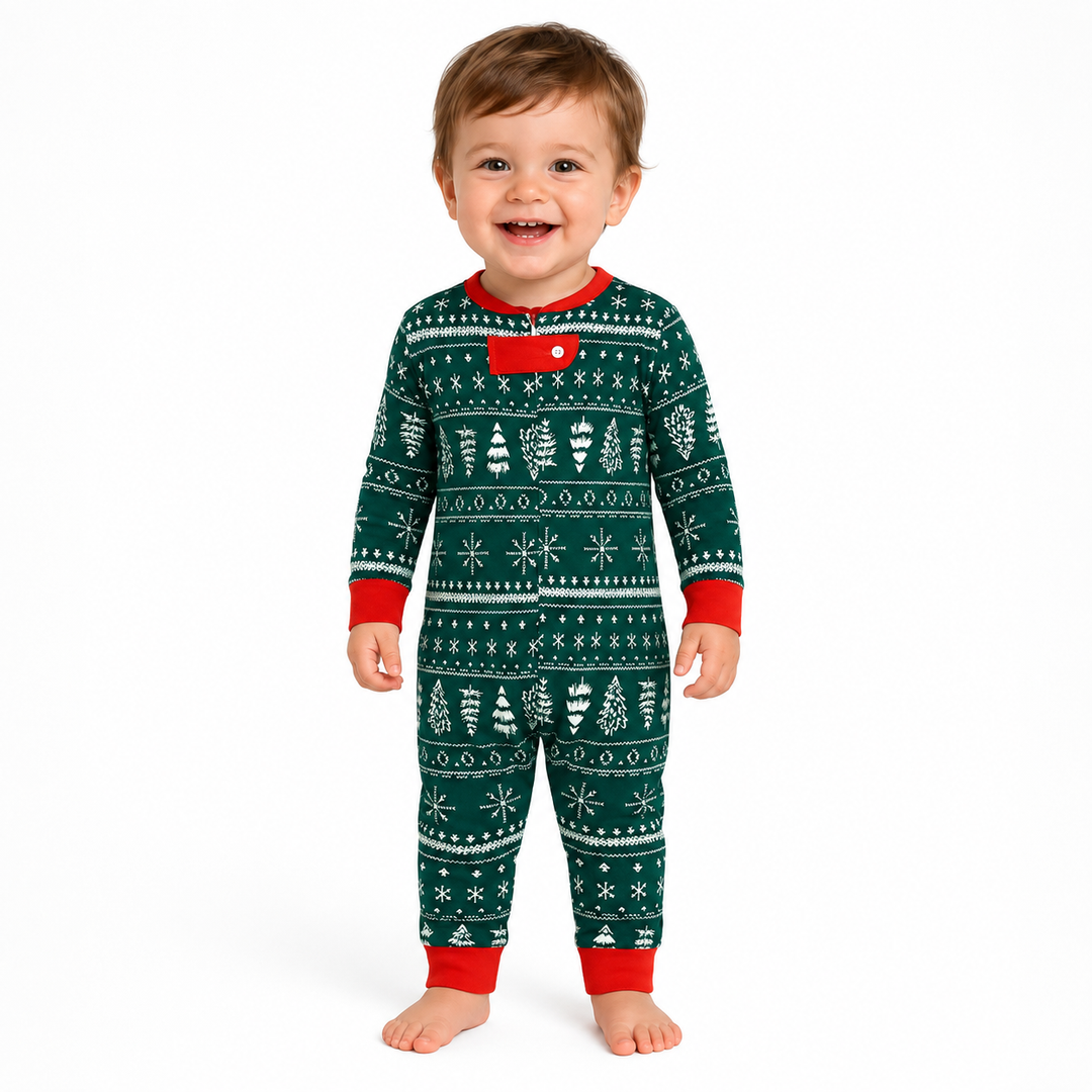 Baby wearing green Christmas pajamas with white holiday print and red trim on a clean white background.