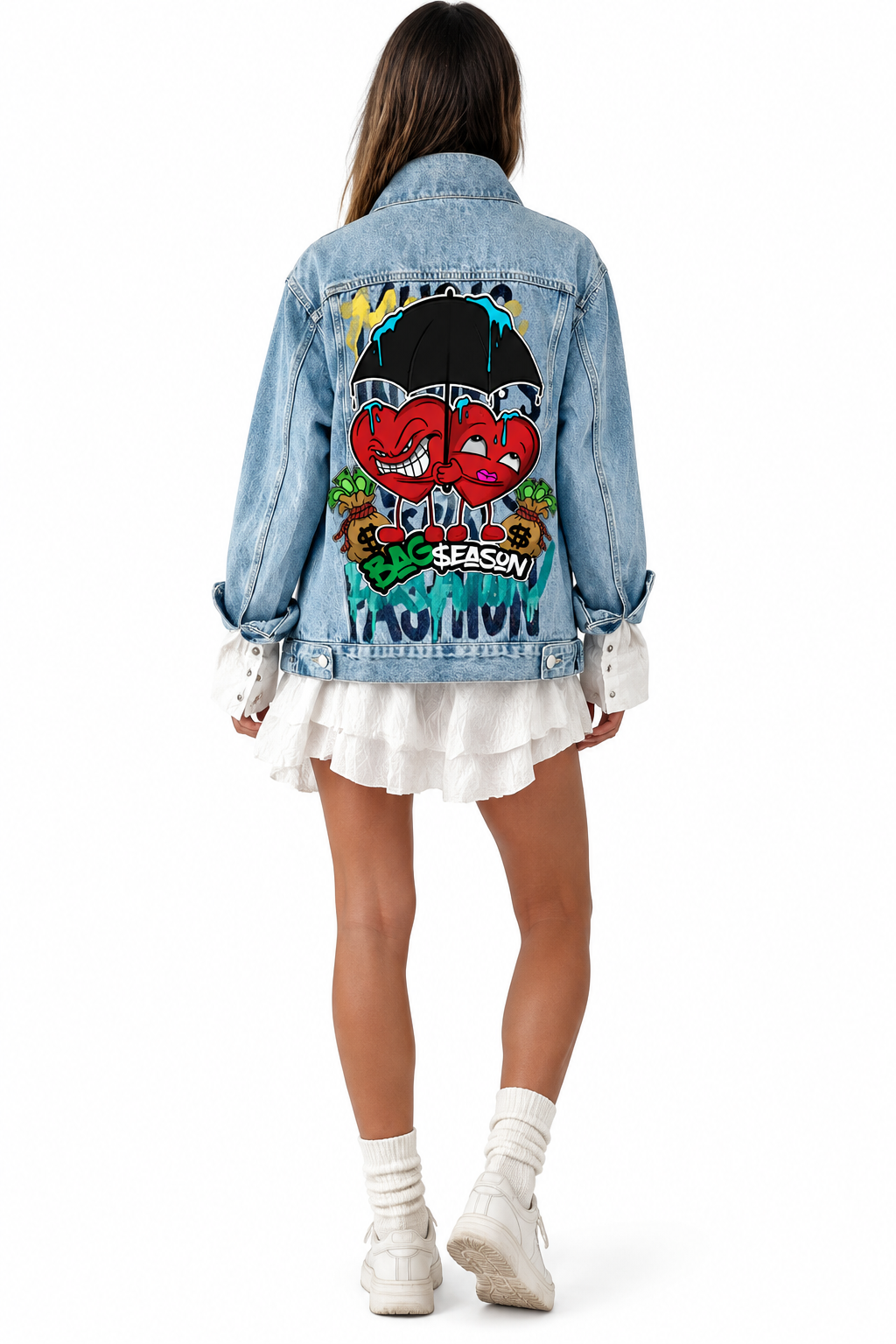 A model shown from the back wearing a light blue denim jacket with a large colorful graphic print on the back, layered over a white ruffled mini skirt, white socks, and white sneakers on a white background.