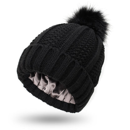 Dark gray satin lined knit beanie with plush pom pom detail, hair friendly interior to reduce frizz after long cold days