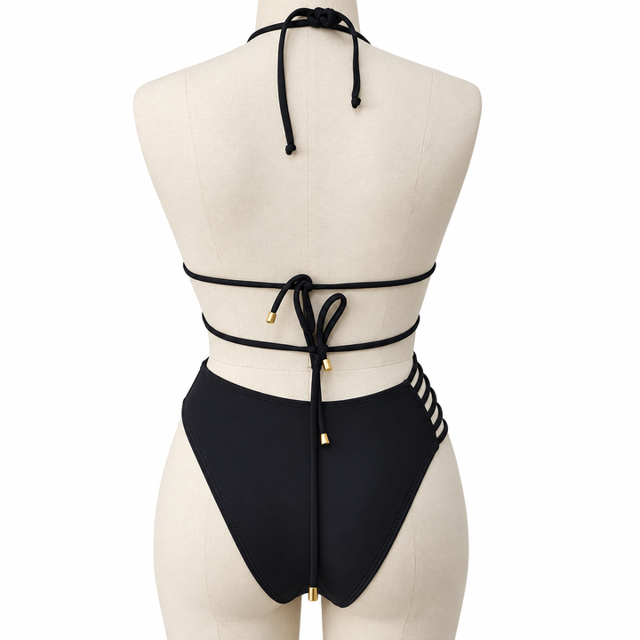 Black bikini back tie detail on a display mannequin, showing the knots, cords and gold-colored tips against a white backdrop.