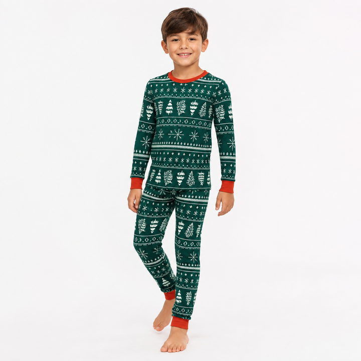 Boy modeling green Christmas pajamas with white holiday print and red trim in a natural studio pose.