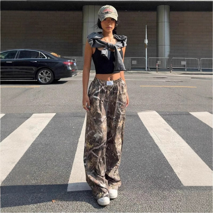 Person wearing a black crop top and camouflage pants standing on a crosswalk.
