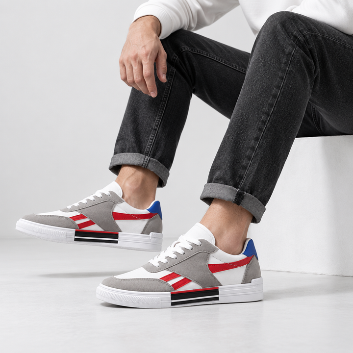 Male model wearing red striped canvas shoes with gray overlays, white laces and blue heel tab in a clean studio.
