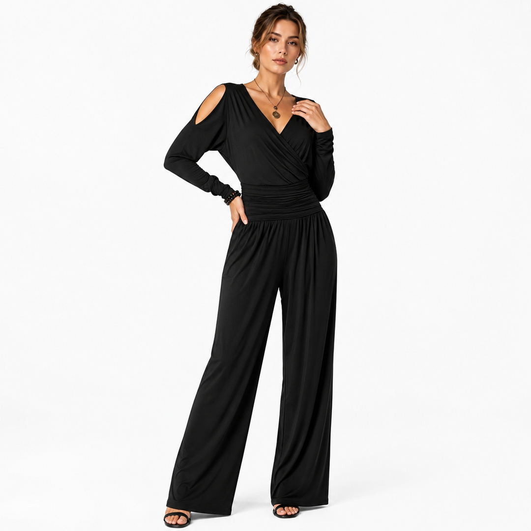 Black Milk Silk jumpsuit on a woman in a three-quarter pose, showing V-neck wrap detail, cold shoulders, ruched waist and wide legs.