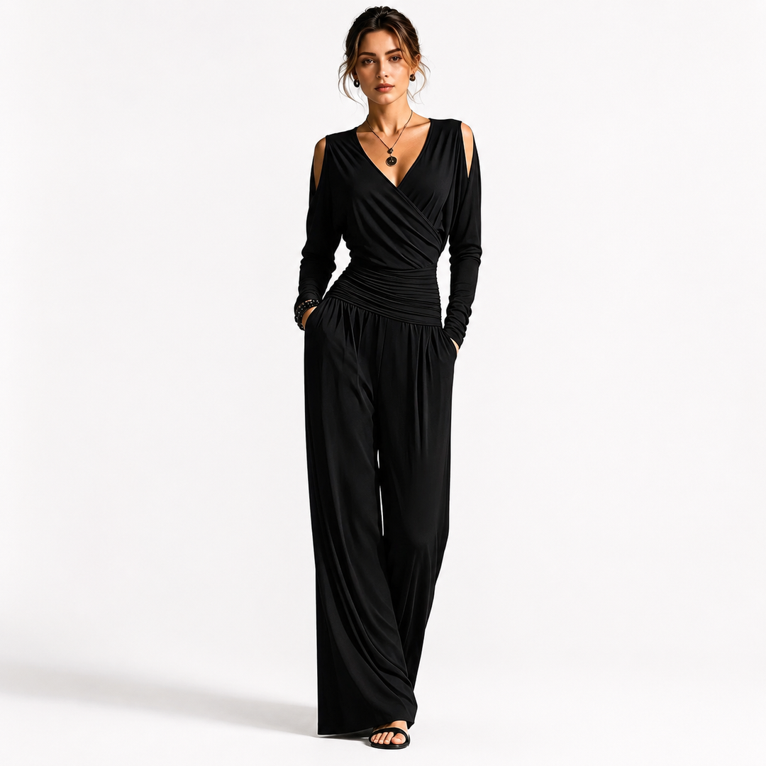 Black Milk Silk jumpsuit on a woman with visible face, V-neck wrap bodice, cold-shoulder sleeves, ruched waist and wide-leg pants.