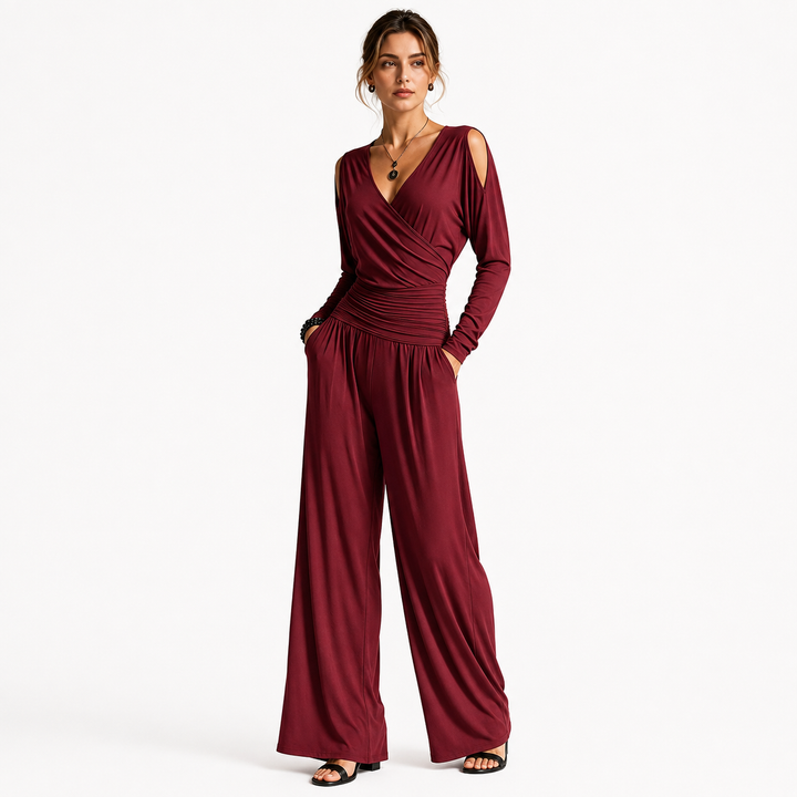 Wine Red Milk Silk jumpsuit on a woman in an angled pose, showing the wrap V-neck, cold shoulders, ruched waist and flowing wide legs.
