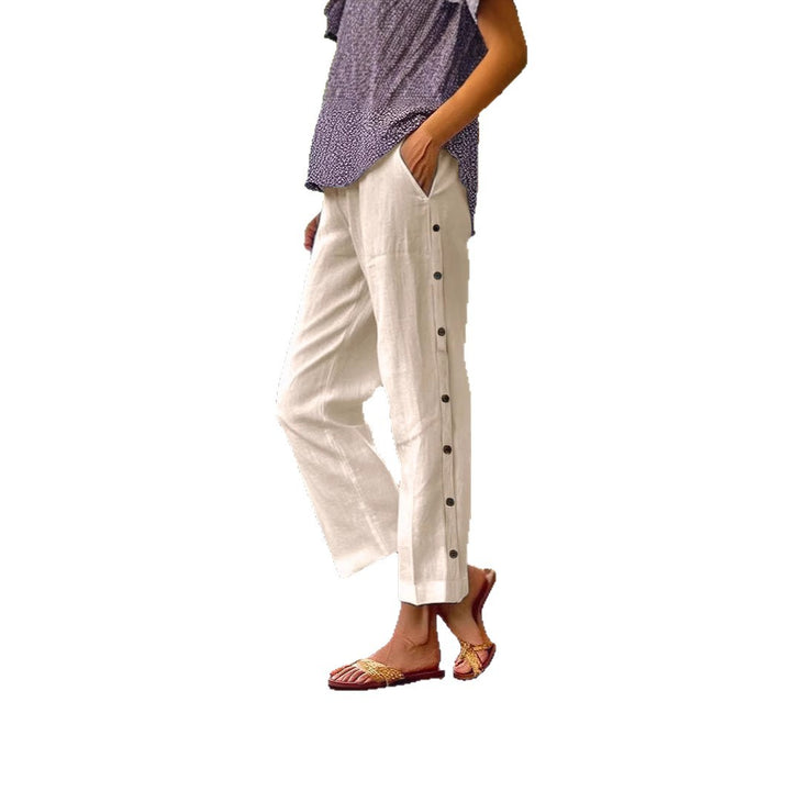 Person wearing white pants with black buttons on a white background