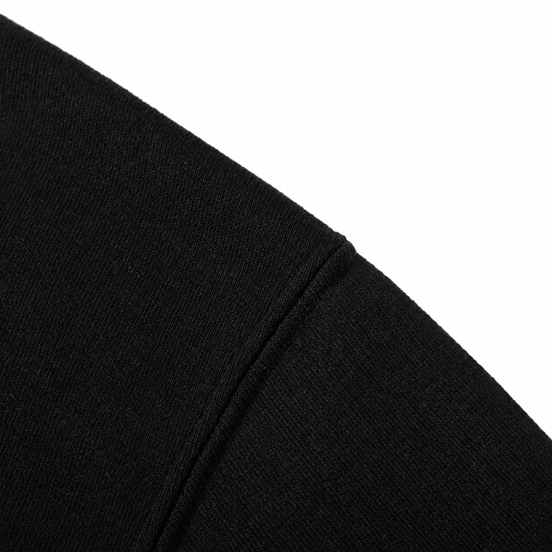 Close-up of black hoodie fabric and the shoulder seam on a white background.
