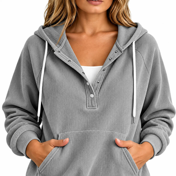Detail of a gray hooded top with snap buttons, white drawstrings, ribbed front surface and kangaroo pocket on an adult model.