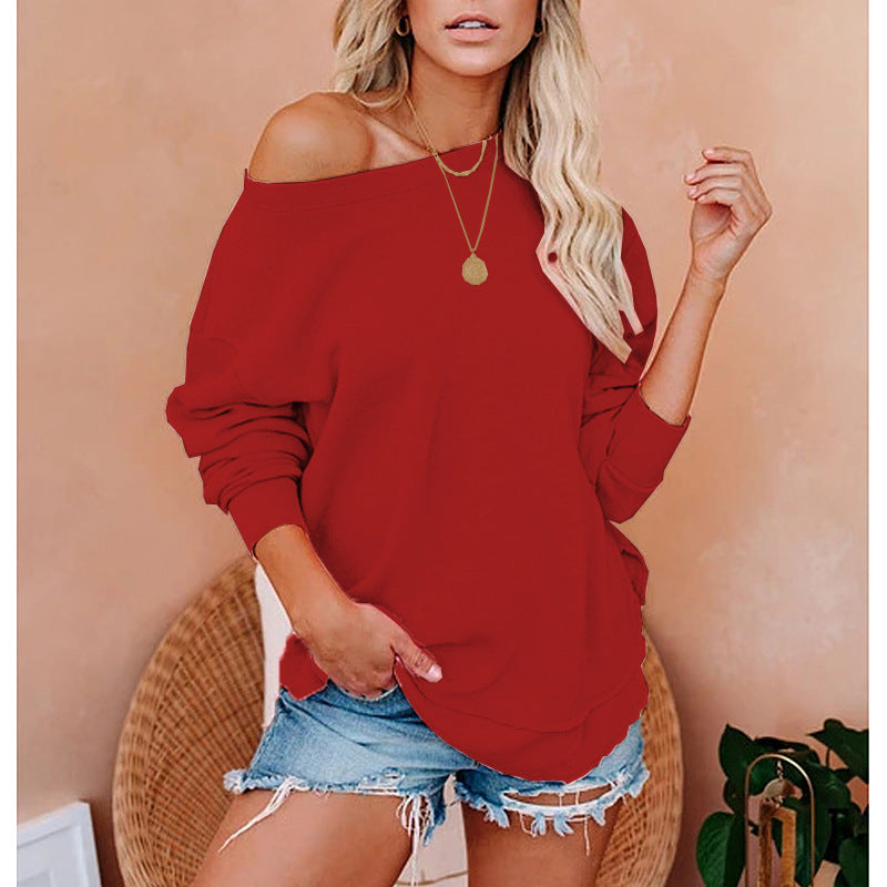 Woman wearing a red off-shoulder top and denim shorts against a beige wall.