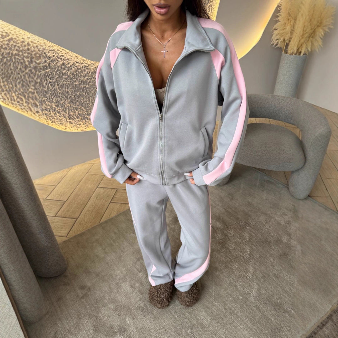 Person wearing a gray tracksuit with pink accents in an indoor setting.