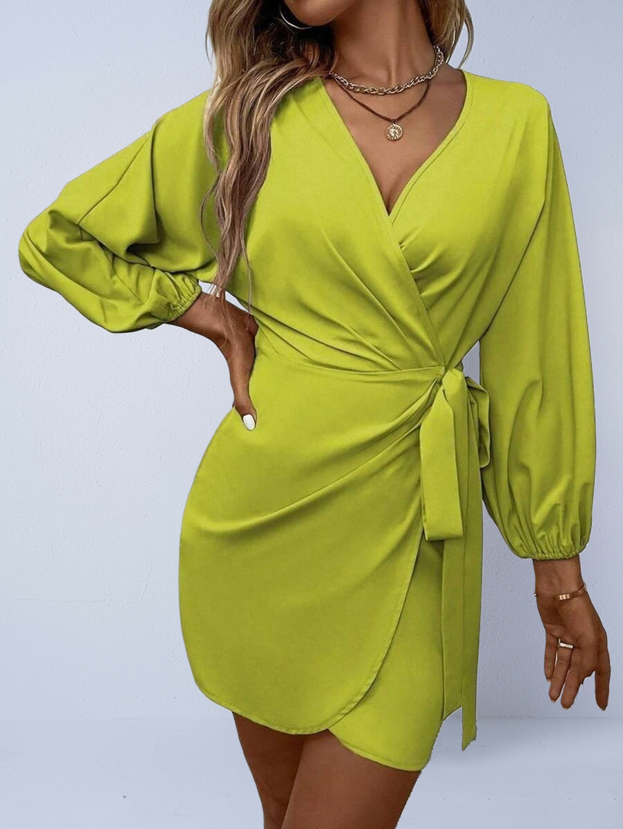 Woman wearing a bright green dress with long sleeves on a light gray background