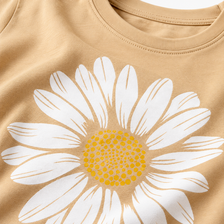 Close-up of the white and yellow daisy print on the khaki cotton T-shirt, showing the graphic and visible surface texture.