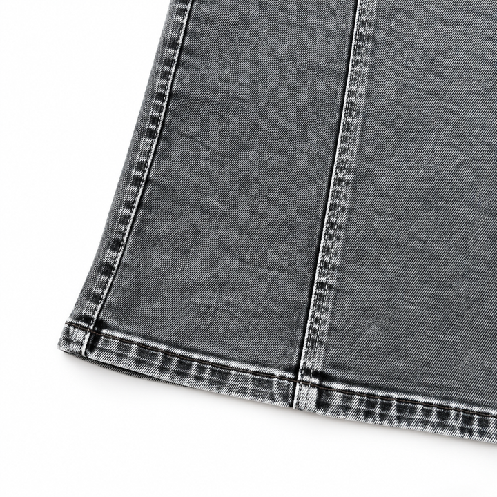 Close-up of the Black Grey dress laid flat on white, showing washed denim, the lower seam and stitched hem without any model.