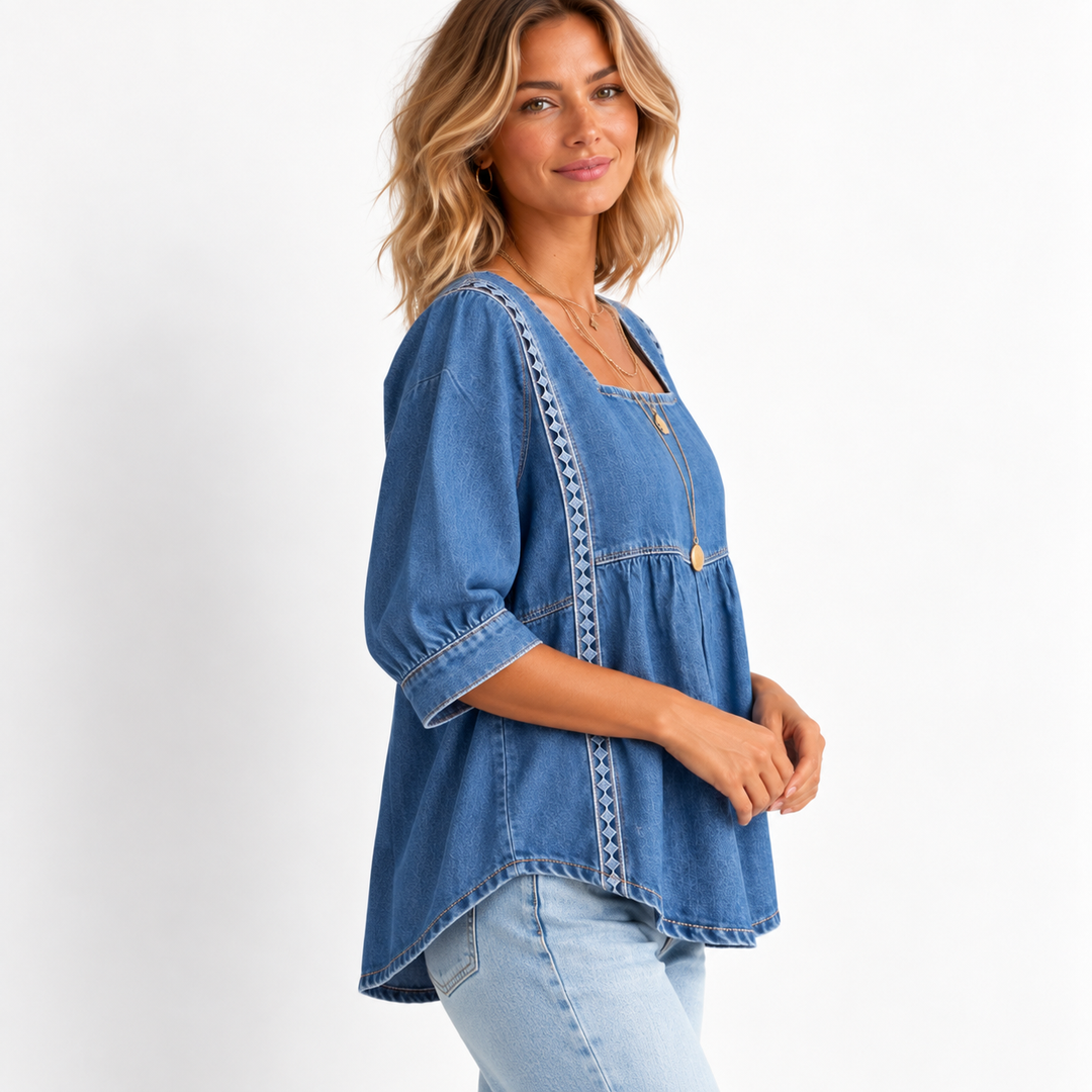 Side view of the denim blouse on a model showing the square neckline, gathered seam and lace patchwork trim.