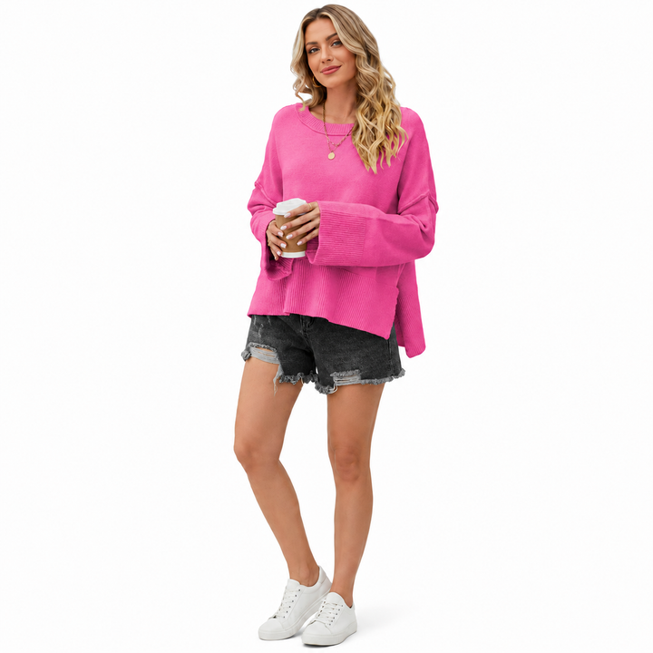Pink dropped shoulder sweater on a woman with flare sleeves, ribbed cuffs and casual styling on a clean white studio background