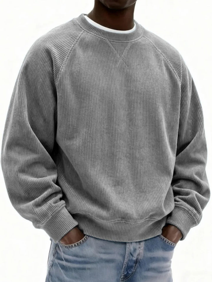 Person wearing a gray ribbed sweater and light blue jeans on a white background