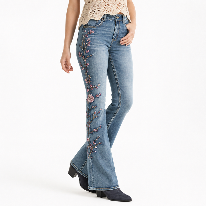 Flared jeans for women hero fit view with high waist blue denim wash, pink floral embroidery and flared legs on white studio.
