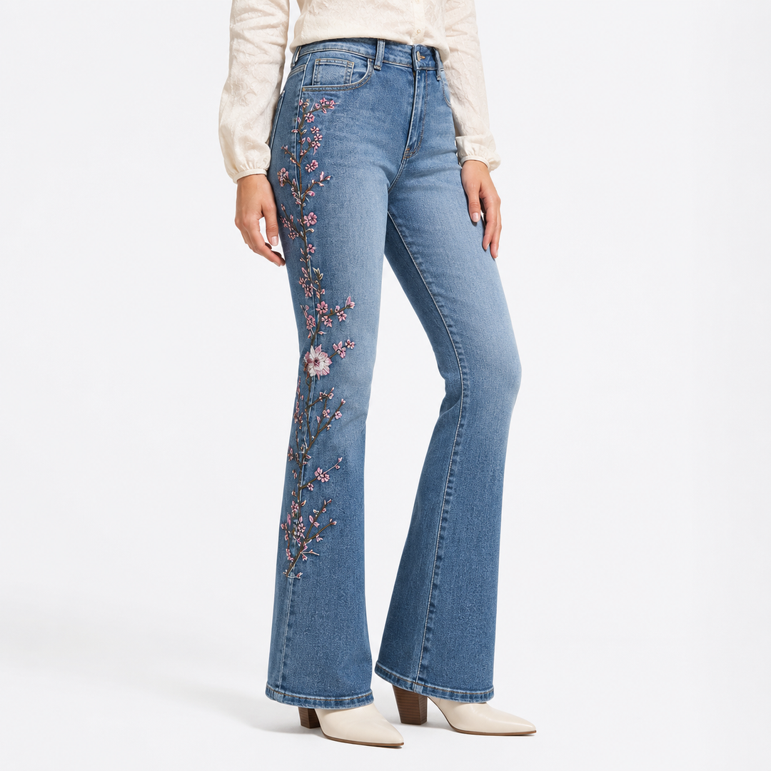 High-waisted embroidered denim jeans, in three-quarter view, showing blue wash, floral side detail and flared leg silhouette.