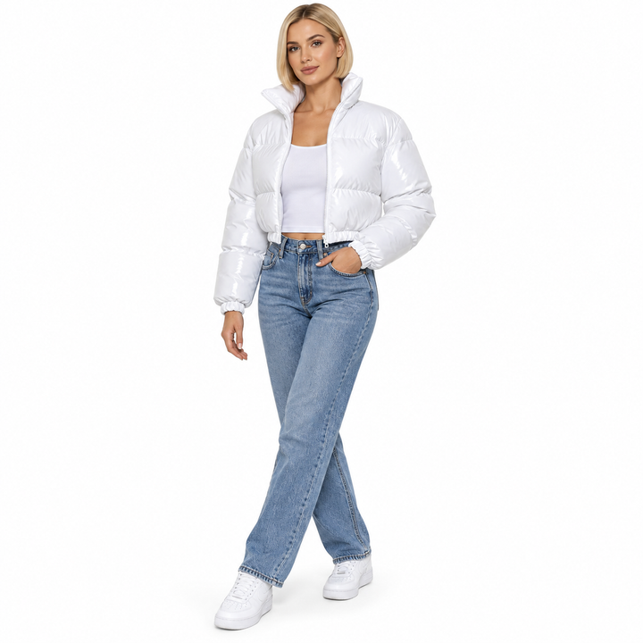 Blonde model wearing a white cropped jacket with blue jeans and white sneakers.