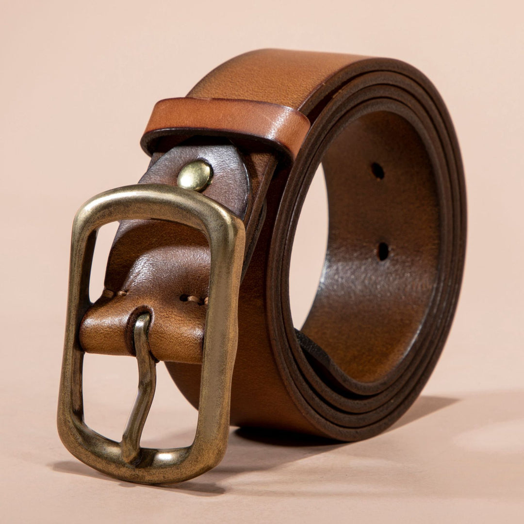 Brown leather belt with brass buckle on a beige background