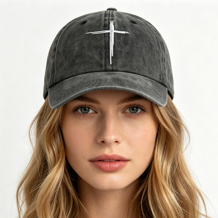 Person wearing a black baseball cap with a white cross on a white background