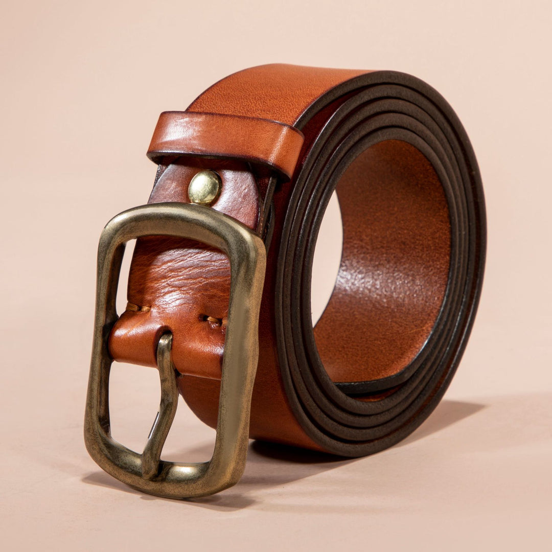Brown leather belt with a brass buckle on a beige background