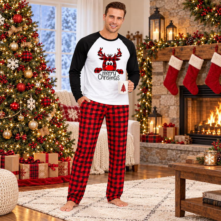 Dad in matching holiday pajamas beside a decorated tree and fireplace