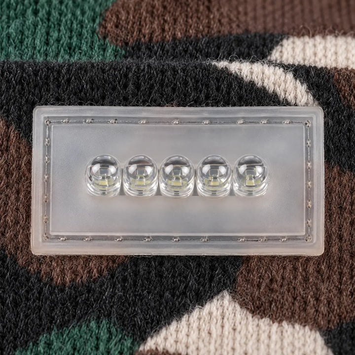 Close-up view of the transparent five-light module attached to knit fabric, showing five separate lenses and outer stitching.