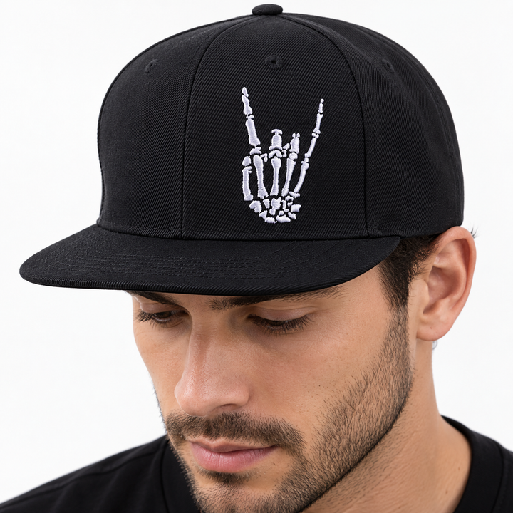 Close-up of the black flat brim baseball cap showing the front skeleton-hand graphic, brim stitching and visible fabric texture.