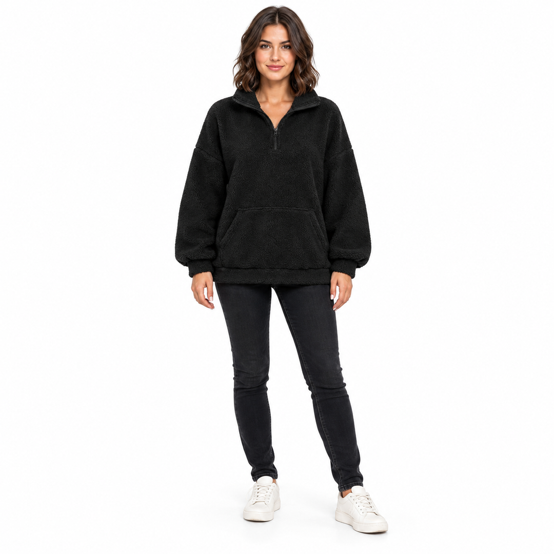 Black fleece pullover on a full-length brunette model facing forward, showing a raised collar, front zipper and pouch pocket.