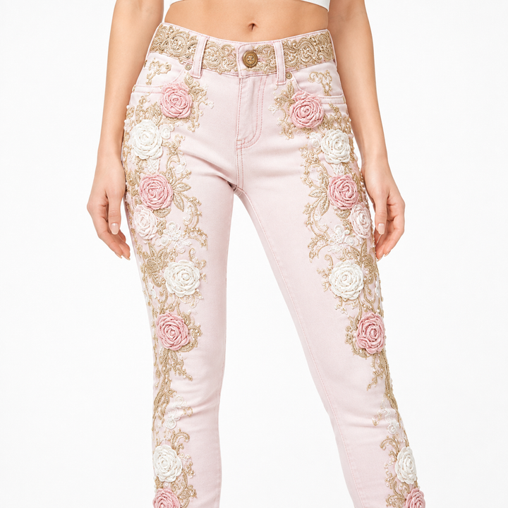 Close-up of pink floral embroidered jeans with raised rose appliques, gold vines, waistband and stitching