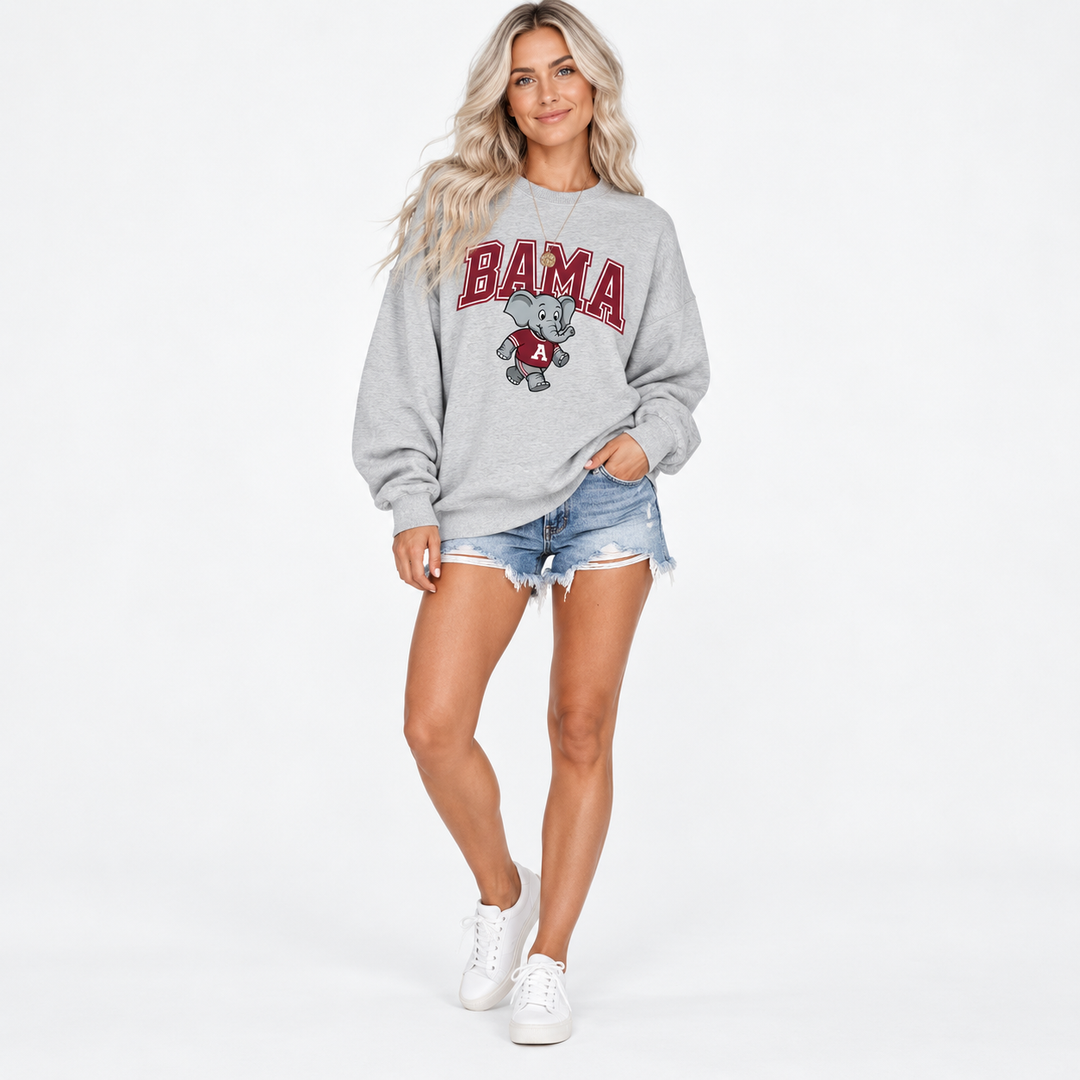 Full-body studio view of female model wearing gray elephant-print sweatshirt and denim shorts