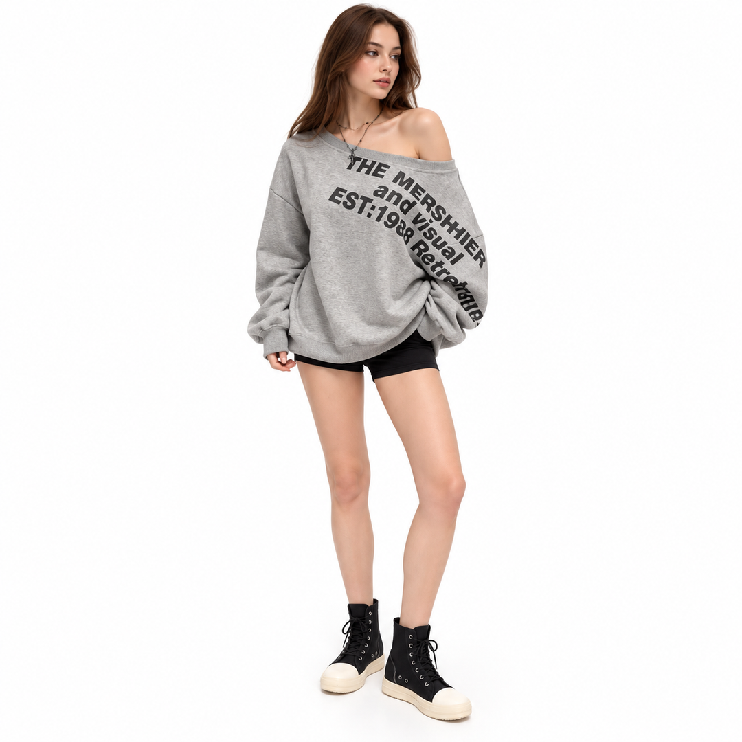 Grey printed pullover shown from a front angle on a female model, showing a wide neckline and long sleeves in a white studio.