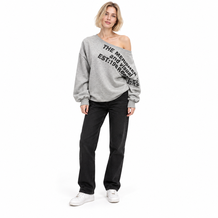 Second model in the grey printed pullover with blonde bob, black jeans and white trainers, shown full body in a white studio.