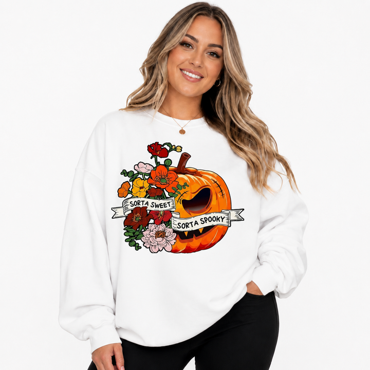 Woman wearing white floral pumpkin sweatshirt with Sorta Sweet Sorta Spooky graphic on a clean white studio background.